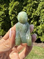 Front view of the green jade kneeling figure showing facial and clothing details.