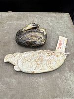 Photo showing both carved jade items, the duck and fish, on a fabric surface with provenance and sale info in seller notes.