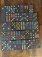 Overall view of the antique carved and painted wood domino pieces laid out to show colors, details, and condition.