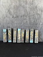 Front view of 8 antique Chinese Chinese ink sticks with dragon motifs and colored accents showing varying designs.