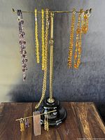 Full view of seven necklaces and three pairs of earrings on two stands showing antique Czech faceted coloured glass beads in amber, purple, and yellow tones.