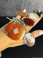 Hand holding six sterling silver jewelry pieces with agate stones