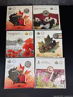 Six commemorative folders arranged in two rows of three showing front artwork and embedded coins