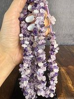 Close-up showing the chunky multi-strand amethyst beads with various sizes and shades of purple and translucent white, highlighting the boulder-style with natural texture.