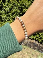 Bracelet worn on wrist in natural light, showing champagne shaded pearls with smooth oval shapes and glossy finish.