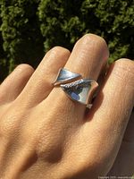 Ring worn on finger showing sculptural contemporary design and diamond accent