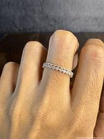 Ring worn on finger showing crown-style design and clear stones around the band.