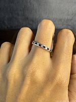 Photo of sterling silver eternity ring with clear and black stones worn on finger, showing the band and stones around it.