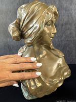 Side-angle view showing the headscarf, tied back hairstyle, and profile of the woman's face with draped clothing on shoulders.