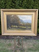 Front view of framed oil painting on decorative easel outdoors