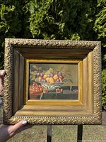 Front view of framed still life painting held outdoors