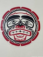 Close-up of one of the sealed artist proof prints showing the detailed Indigenous moon face art in red and black. The print includes artist signature and edition number.
