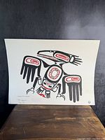 Full view of the white textured paper art print featuring the black and red raven with spread wings against a dark background.