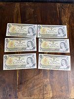 Top view of six Canadian one dollar bank notes front side showing Queen Elizabeth II portrait