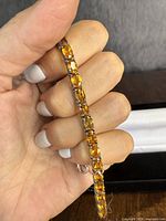 Close-up photo of the sterling silver bracelet showing oval natural citrine gemstones set in each link held by hand.