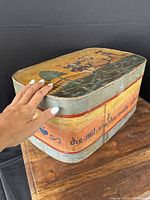 Three-quarter view of box exterior with hand for scale