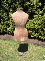 Full front view of child's dress form with rod and cast-iron base outdoors