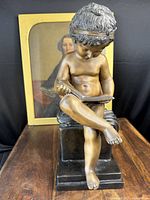 Front view of the bronze sculpture showing the boy's face and book.