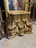 Front angled view of stand showing carved acanthus leaf details and foot areas