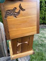 Angled photo showing box top with carved killer whale and base construction with visible wood grain and dark corner accents.
