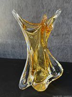 Front side view of the large vase showing free-form sculptural shape in amber and clear glass