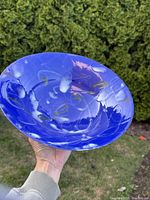 Front view of the large blue glazed shallow pottery bowl showing hand-painted decorative details and glossy finish.