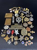 Full collection of assorted military and related pins, medals, and insignia arranged on black background.