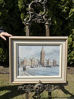 Full view of the framed painting displayed on an easel outdoors