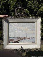 Front view of the framed oil painting showing sail boats along a dock with cloudy sky.