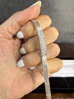 Close-up of the bracelet held in hand showing mesh band and clear stones on the central bar.