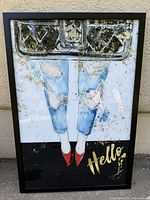 Framed vintage acrylic poster showing legs in ripped jeans and red shoes with 'Hello' text.