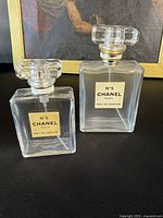 Two vintage original Chanel No. 5 Eau de Parfum bottles displayed upright with their glass stoppers on.