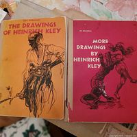 Two softcover art books, 'The Drawings of Heinrich Kley' (orange cover) and 'More Drawings by Heinrich Kley' (red cover), displayed together.