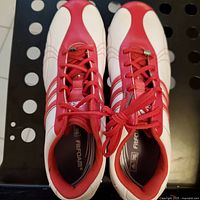 Top view of Adidas golf shoes showing red and white design, lace closure and Adidas stripes.