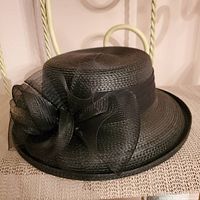 Front angled view of black vintage ladies straw hat with large mesh bow decoration.