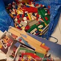 First image showing a large quantity of vintage Lego bricks and pieces, including baseplates and instruction booklets.