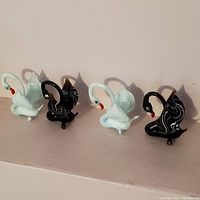 Four Murano glass swan figurines, two white and two black, arranged in a row