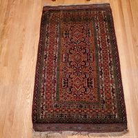 Full top-down view of the vintage Persian hand knotted rug laid flat on wooden floor showing entire design and fringed edge.
