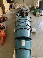 Top view of blue kayak with deck rigging and paddle across cockpit