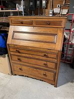 Front view of antique oak writing bureau showing drawers and drop front writing surface