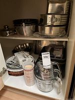 Photo showing stacked stainless steel baking pans and bowls, electric mixer and glass and plastic measuring cups.