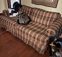 Beautyrest plaid fabric hide-a-bed sofa showing side and front angles with backpacks on it.