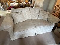 Full front view of the beige floral sofa including matching cushions and armrests, showing fabric pattern and overall condition.