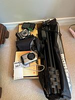 Overhead view showing three Canon PowerShot cameras, Monfrotto tripod in bag, and Lowepro pouch on cardboard