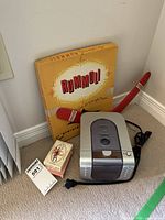 Photo showing Koss CL240-2 CD player, Rummoli game box, playing cards, and a red boomerang object.