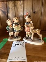 Photo showing both Hummel figurines: #136 Friends (boy and girl) and #49 To Market (girl with deer) side by side