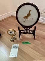 Circular framed silk cat embroidery on rosewood stand and smaller ornate metal stand with panda embroidery.