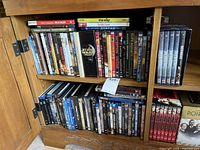 Photo showing two shelves of DVDs and Blu-rays including various titles and box sets like Star Wars Trilogy and Pirates of the Caribbean.