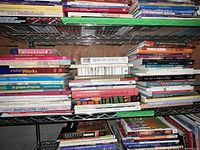 Photo of shelves showing multiple craft and sewing related books including quilting, embroidery, and sewing techniques