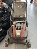 Full top view of lawn mower showing handle, wheels, engine cover, and attached Dust Blocker bag